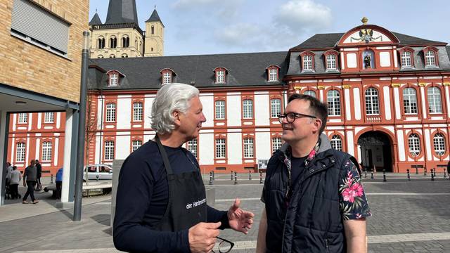 Zwei Männer im Gespräch, im Hintergrund die Abtei Brauweiler.