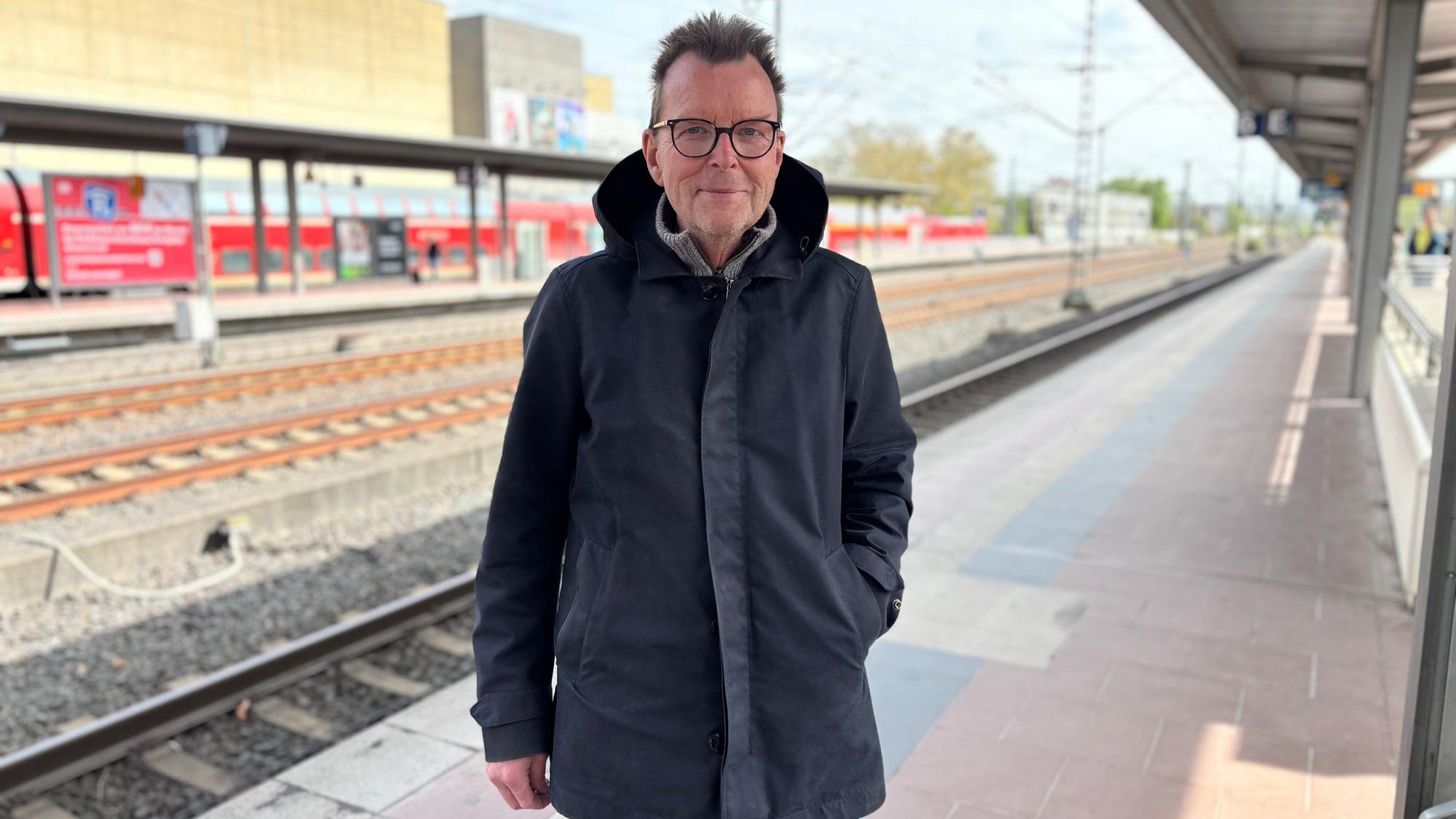 Peter Golzem steht am Siegburger Bahnhof. Im Hintergrund fährt ein Zug ein.