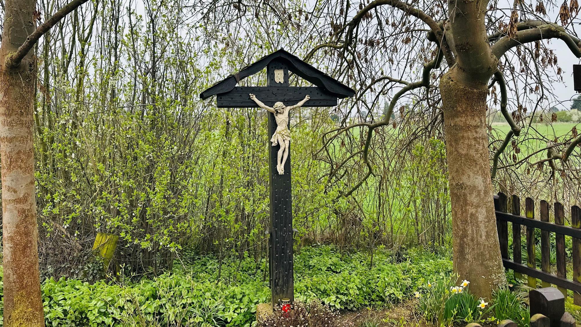 Das zeigt ein Wegekreuz unter Bäumen.