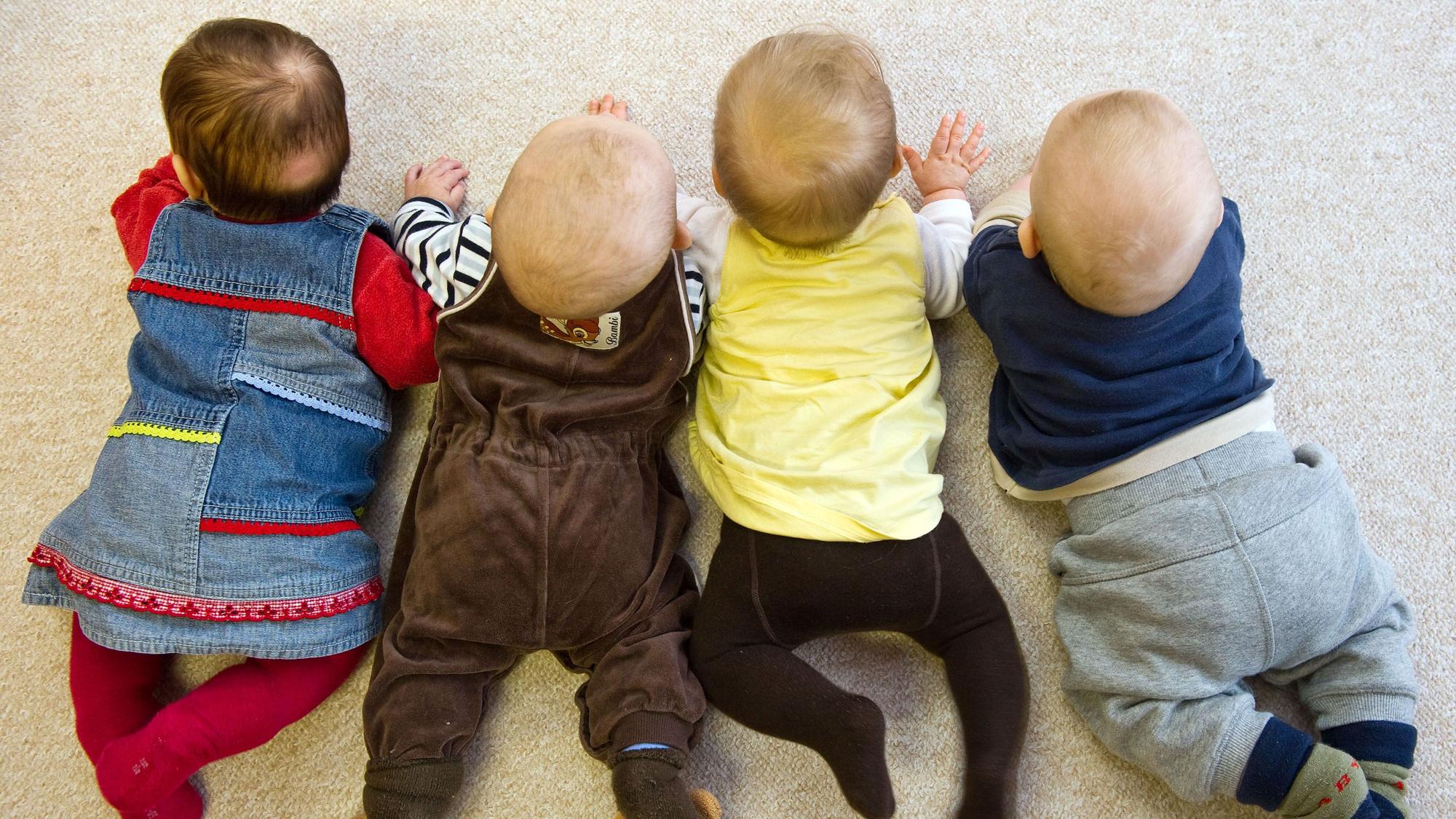 Vier Babys liegen in einer Kita nebeneinander. Die Geburtenhäufigkeit in den NRW-Kommunen und Städten kann weit auseinander liegen.