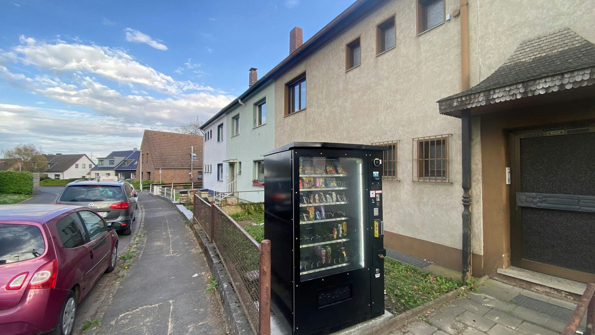 Zu sehen ist eine Verkaufsautomat, der in einem Vorgarten steht.