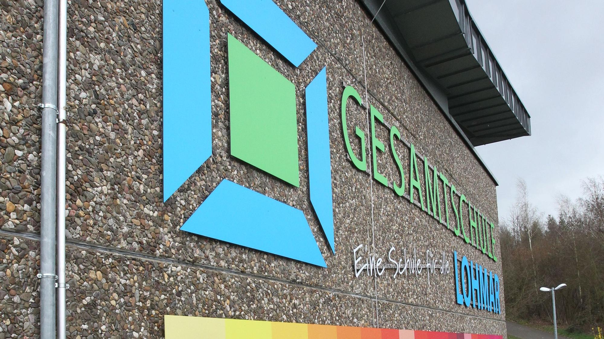 Der Schriftzug der Gesamtschule Lohmar steht neben einem dazugehörigen Logo auf der Wand das Schulgebäudes.