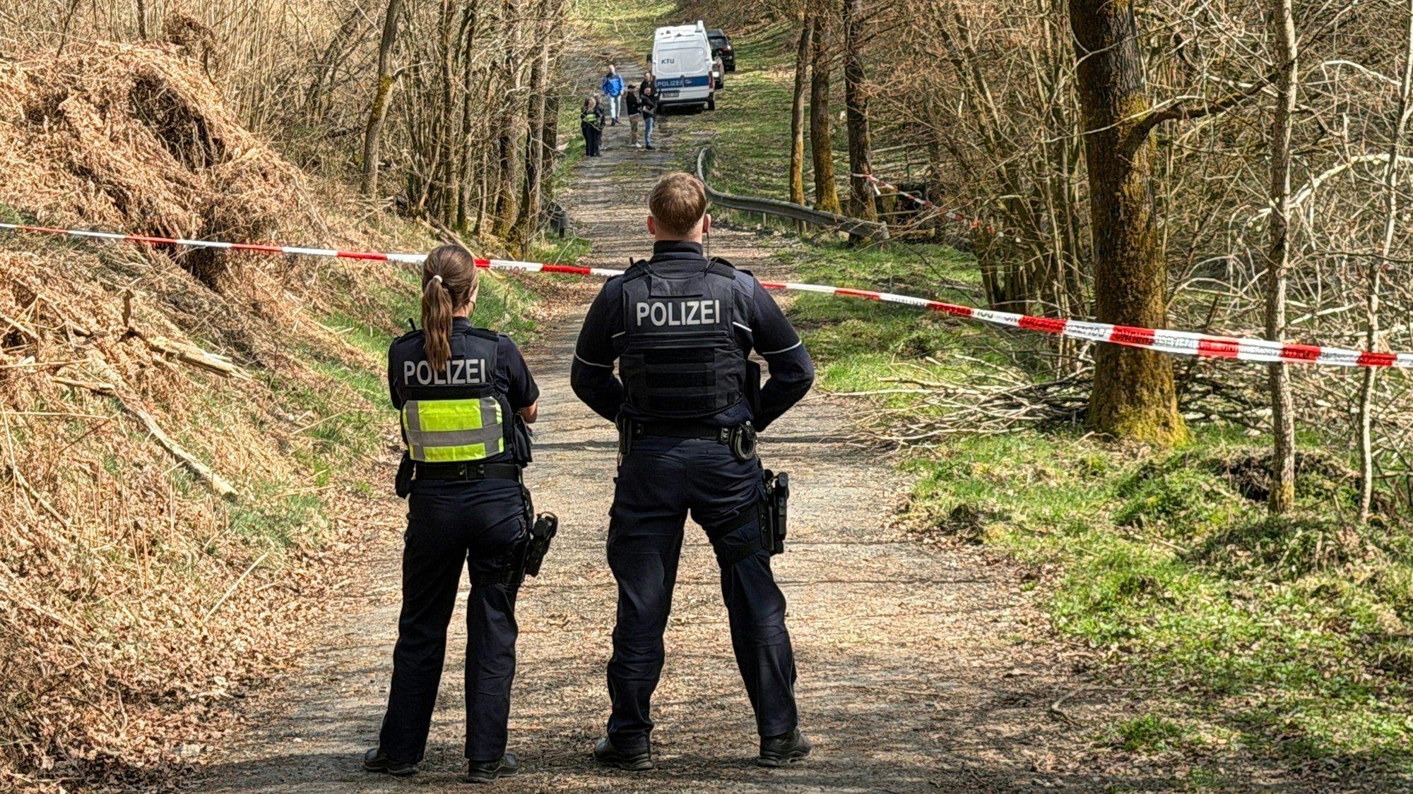 Kräfte der Polizei sind in einem mit Flatterband abgesperrten Bereich eines Waldes in Wenden im Einsatz. Bei einer Müllsammelaktion wurde unweit der A4 ein menschlicher Kopf gefunden.