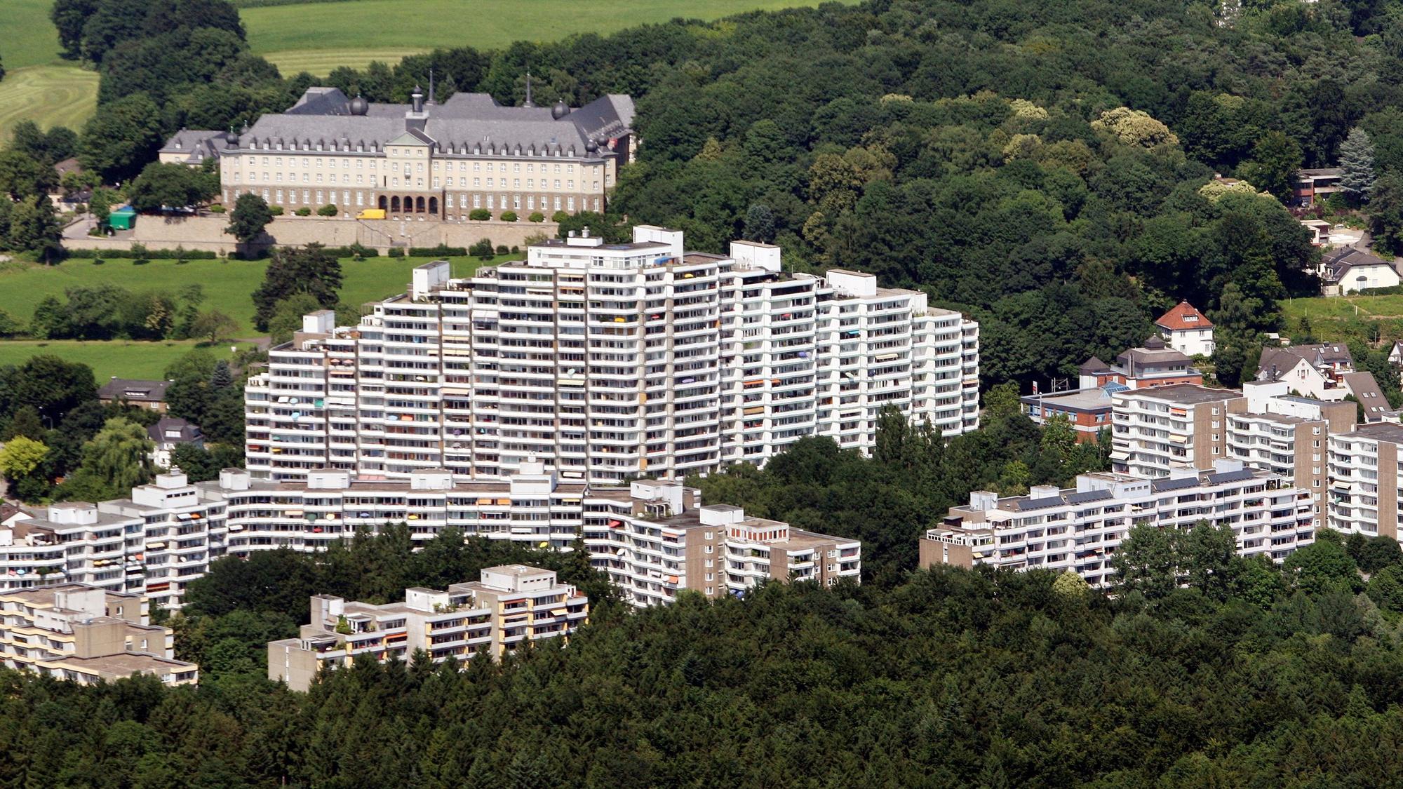 Eine Hochhausssiedlung am Stadtrand. Davor Wald.