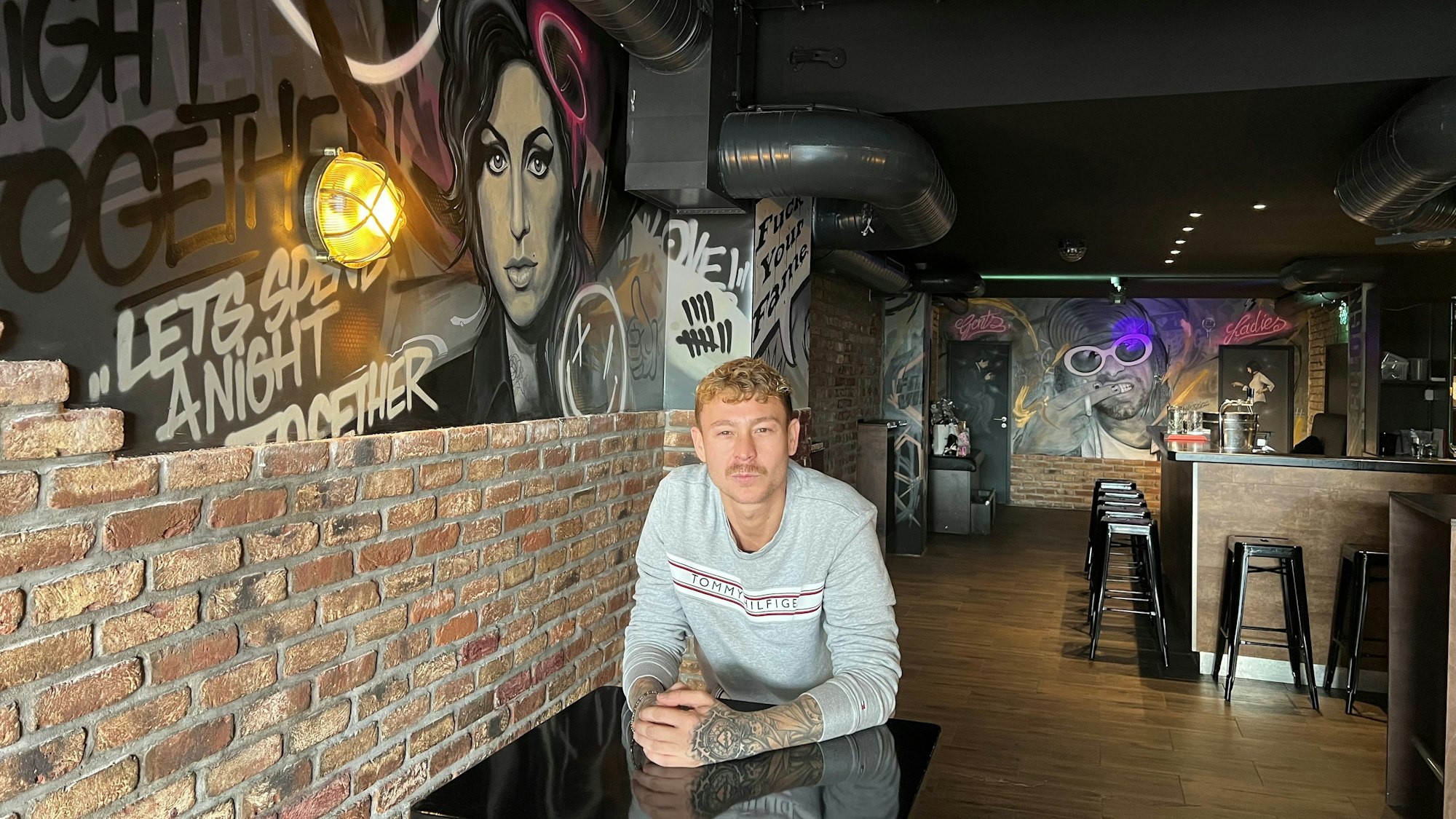 Pascal Dünwald in seiner neuen Retro-Weinbar in der Friesenstraße, wo die beiden Kölner Tattoo-Künstler Daniel Zorg und Janna Oz die gesamte Wandgestaltung ausgeführt haben.
