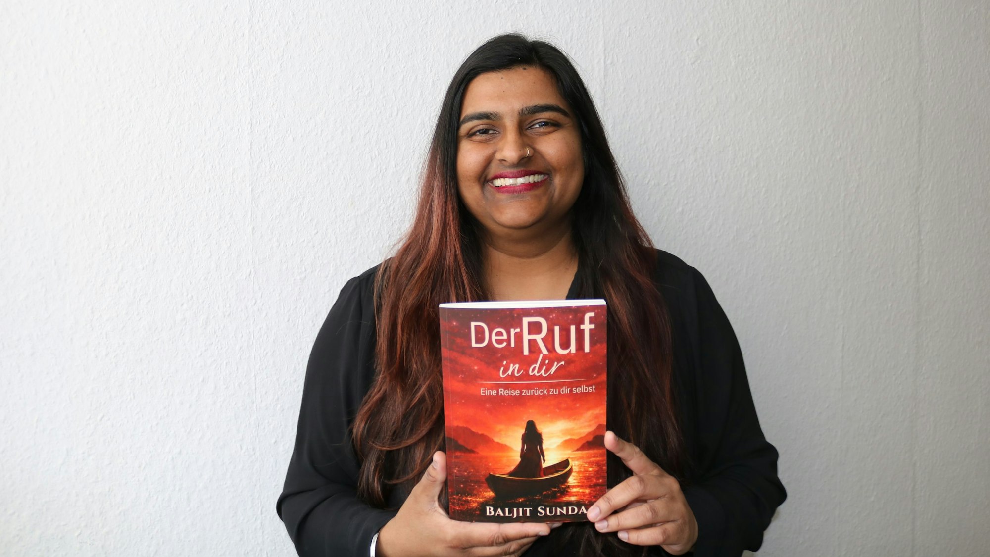 Eine Frau hält ein Buch in der Hand und lächelt.