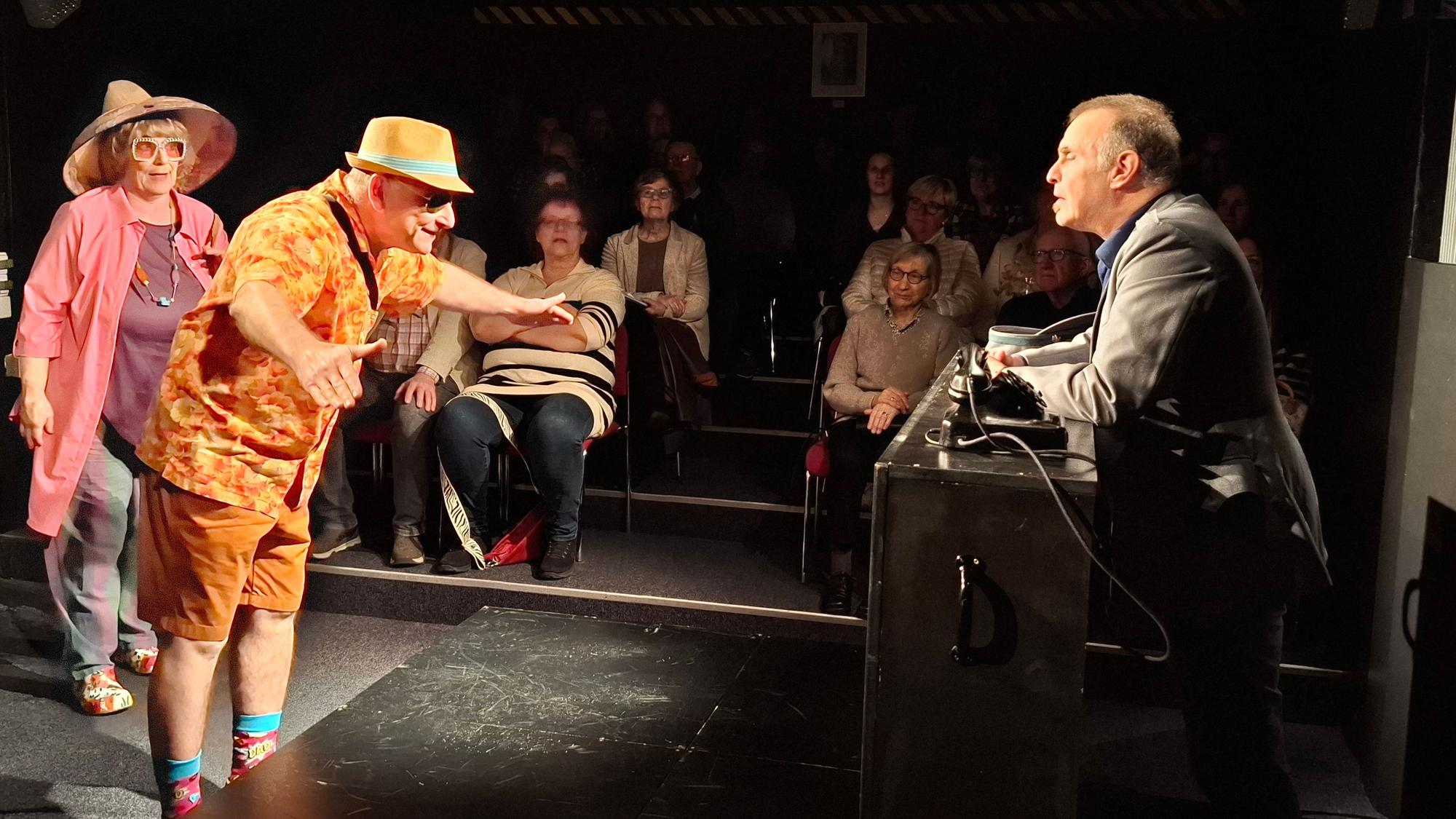 Drei Schauspieler spielen vor Publikum.