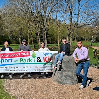 Im Mechernicher Mühlenpark stehen Mitglieder des Organisations- und Trainerteams hinter einem Banner, der das „Sport im Park“-Projekt bewirbt.