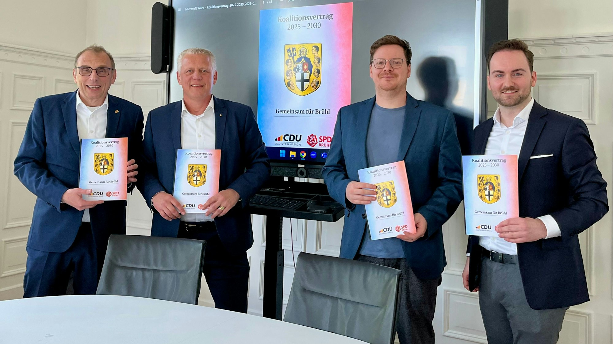 Das Foto zeigt vier Männer vor einem Bildschirm.