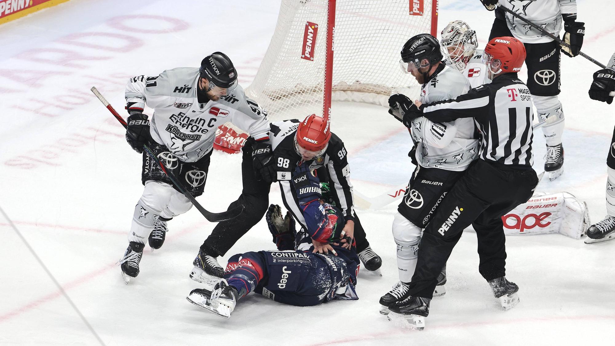 Referees schützen Berlins Ty Ronning nach Zweikampf mit Kölns Torwart Janne Juvonen.