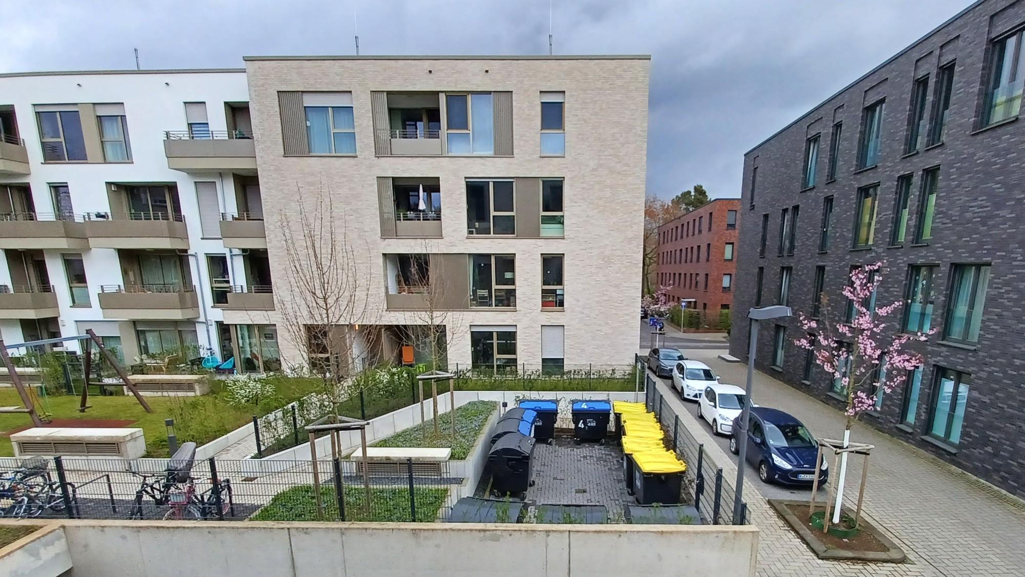 Auf einer Freifläche stehen die 13 Gemeinschafts-Müllcontainer der 2024 eröffneten Wohnanlage.