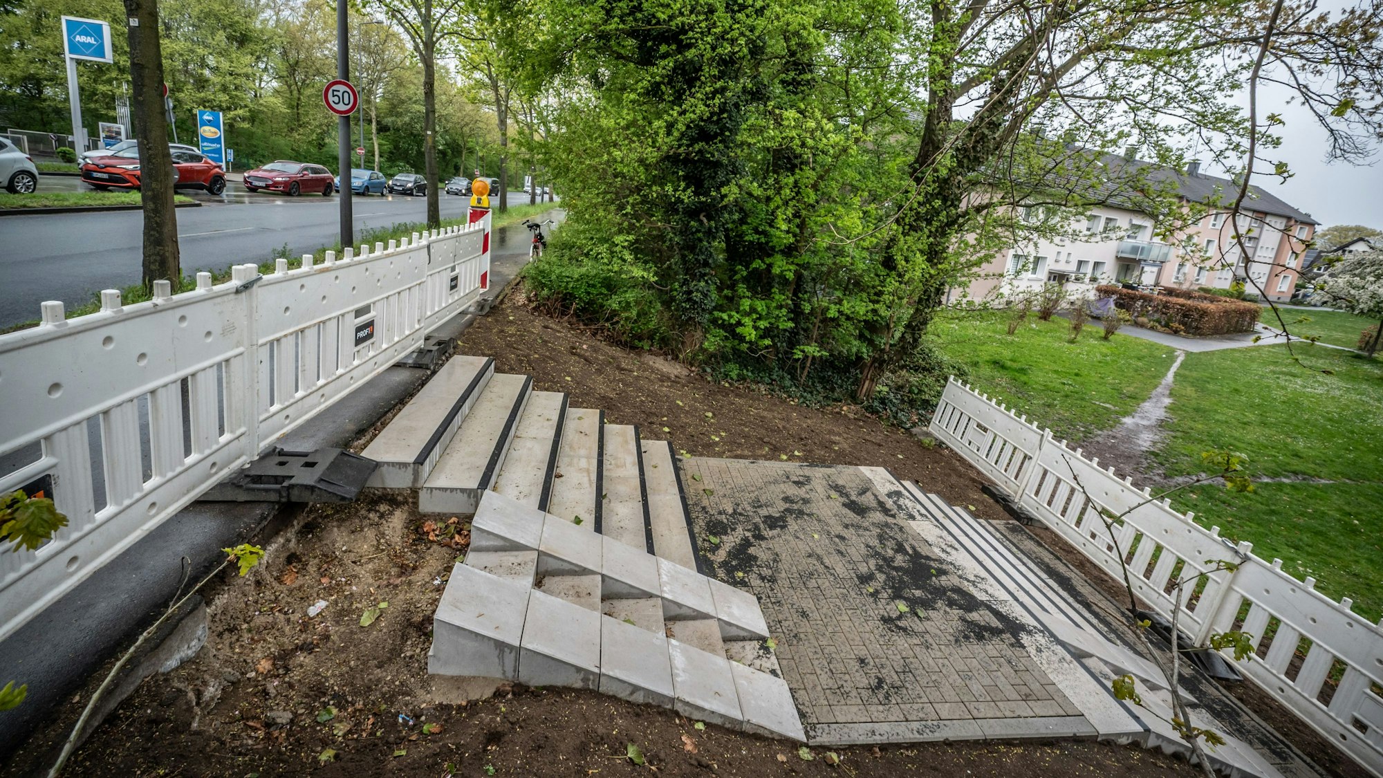 Ein jahrelang als Trampelpfad genutzte Abkürzung vom Willy-Brandt-Ring (links die Aral-Tankstelle) hinunter zur Karl-Krekeler-Straße (rechts) wird jetzt mit einem Treppenabgang offiziell. Bild: Ralf Krieger