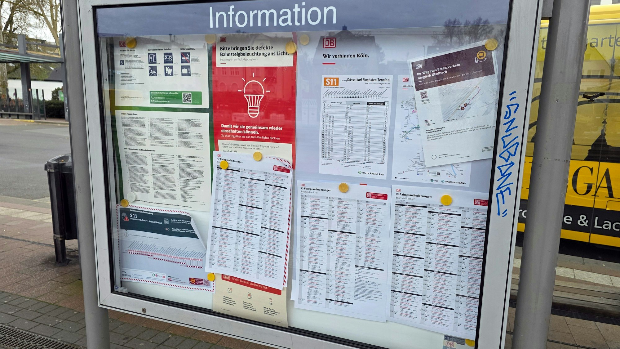 In einem Schaukasten am Gladbacher S-Bahnhof hängen bunt durcheinander verschiedene Infozettel.