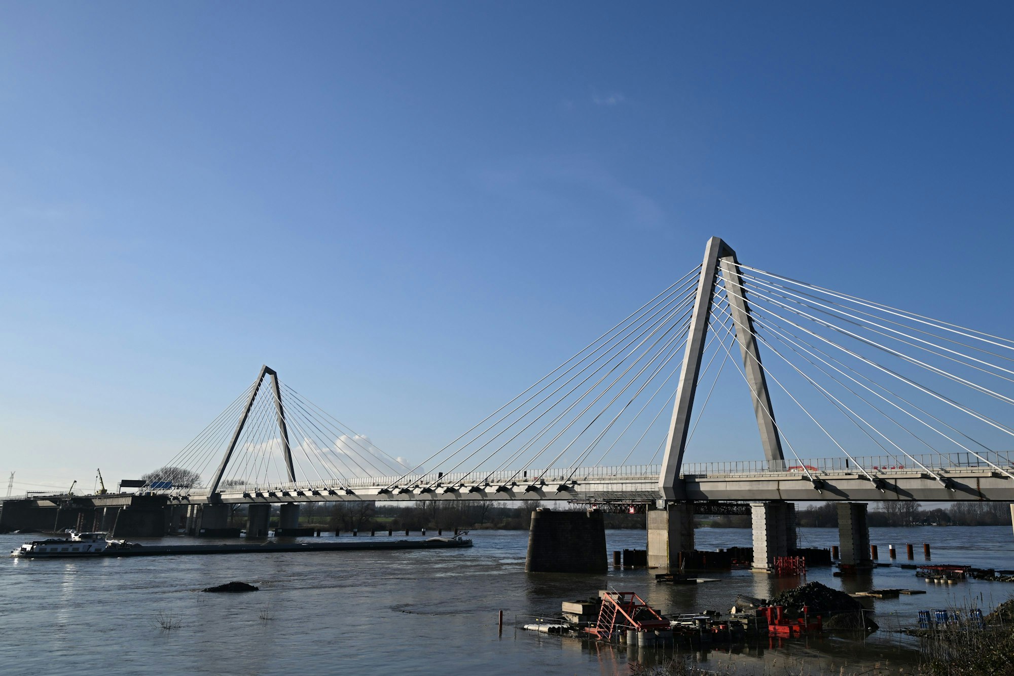 Ein Schiff fährt auf dem Rhein unter der Leverkusener Brücke. Die Leverkusener Rheinbrücke ist aufgrund herabfallender Eiszapfen bis auf Weiteres vollständig gesperrt worden. Gemeinsam mit der Feuerwehr soll nun abtauender Schnee sowie Eis geräumt werden, teilte die Autobahn GmbH mit. Ein Hubschrauber solle die Pylonen überfliegen und die Eisplatten mit dem Wind der Rotorblätter herunter wehen, teilte die Polizei mit. (zu dpa: «Herabfallende Eisstücke: Leverkusener Rheinbrücke gesperrt») +++ dpa-Bildfunk +++