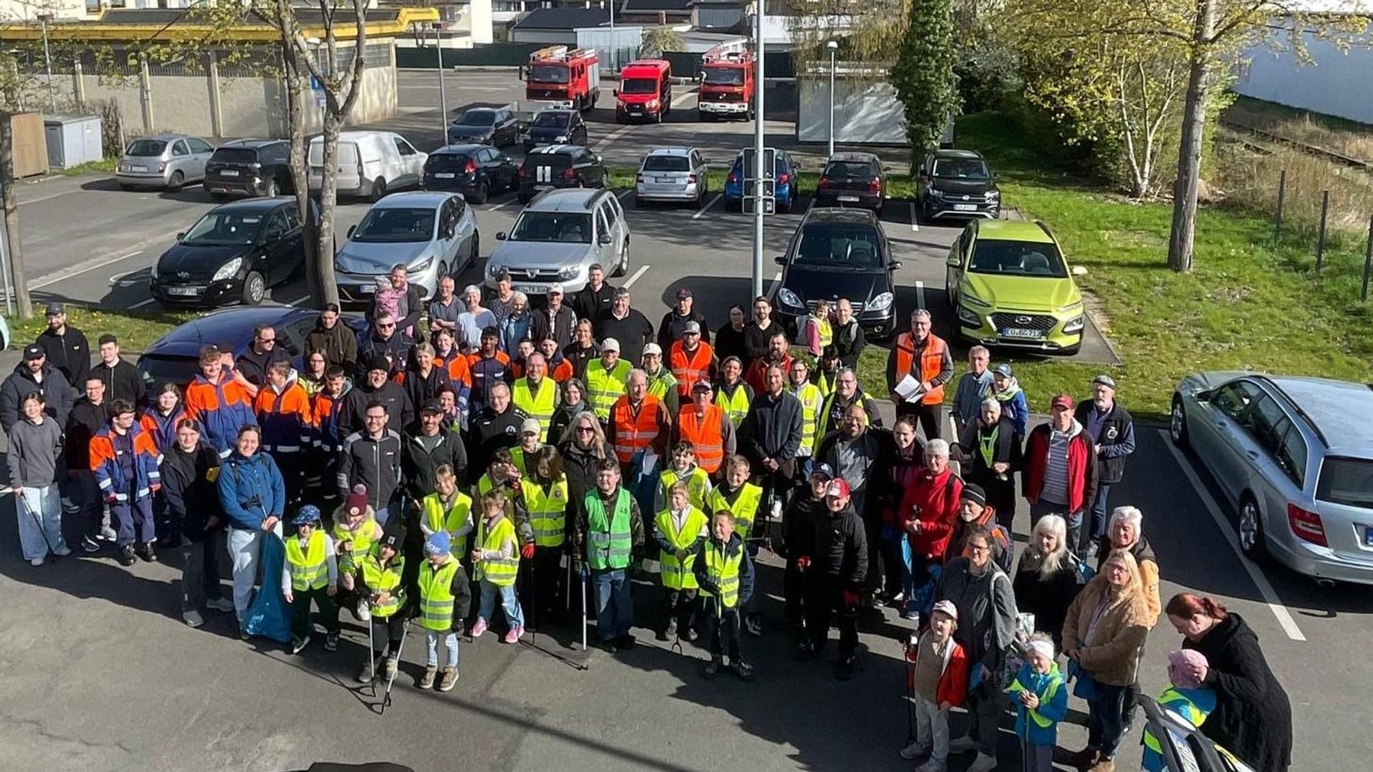 Rund 100 Personen, zum Teil mit gelben Westen bekleidet, stehen nebeneinander.