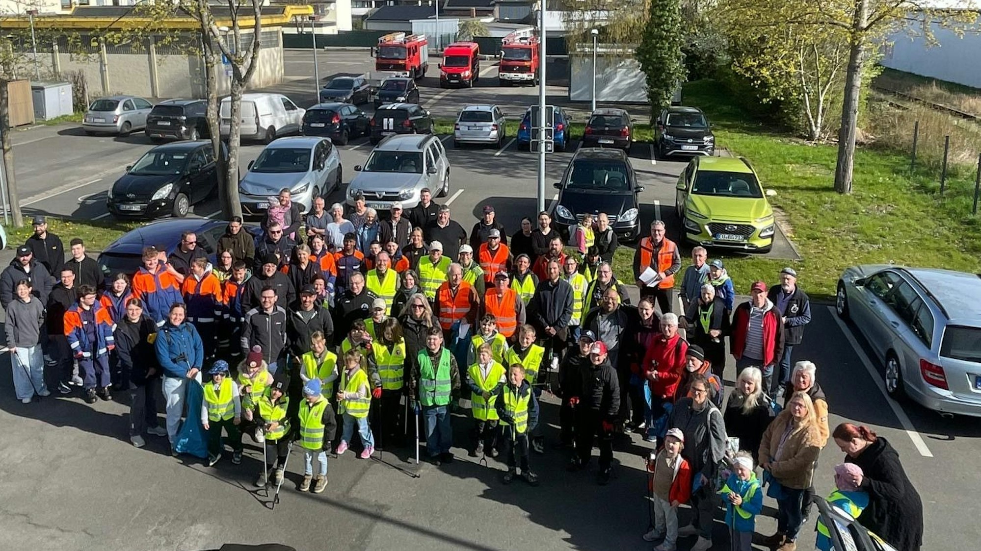 Rund 100 Personen, zum Teil mit gelben Westen bekleidet, stehen nebeneinander.