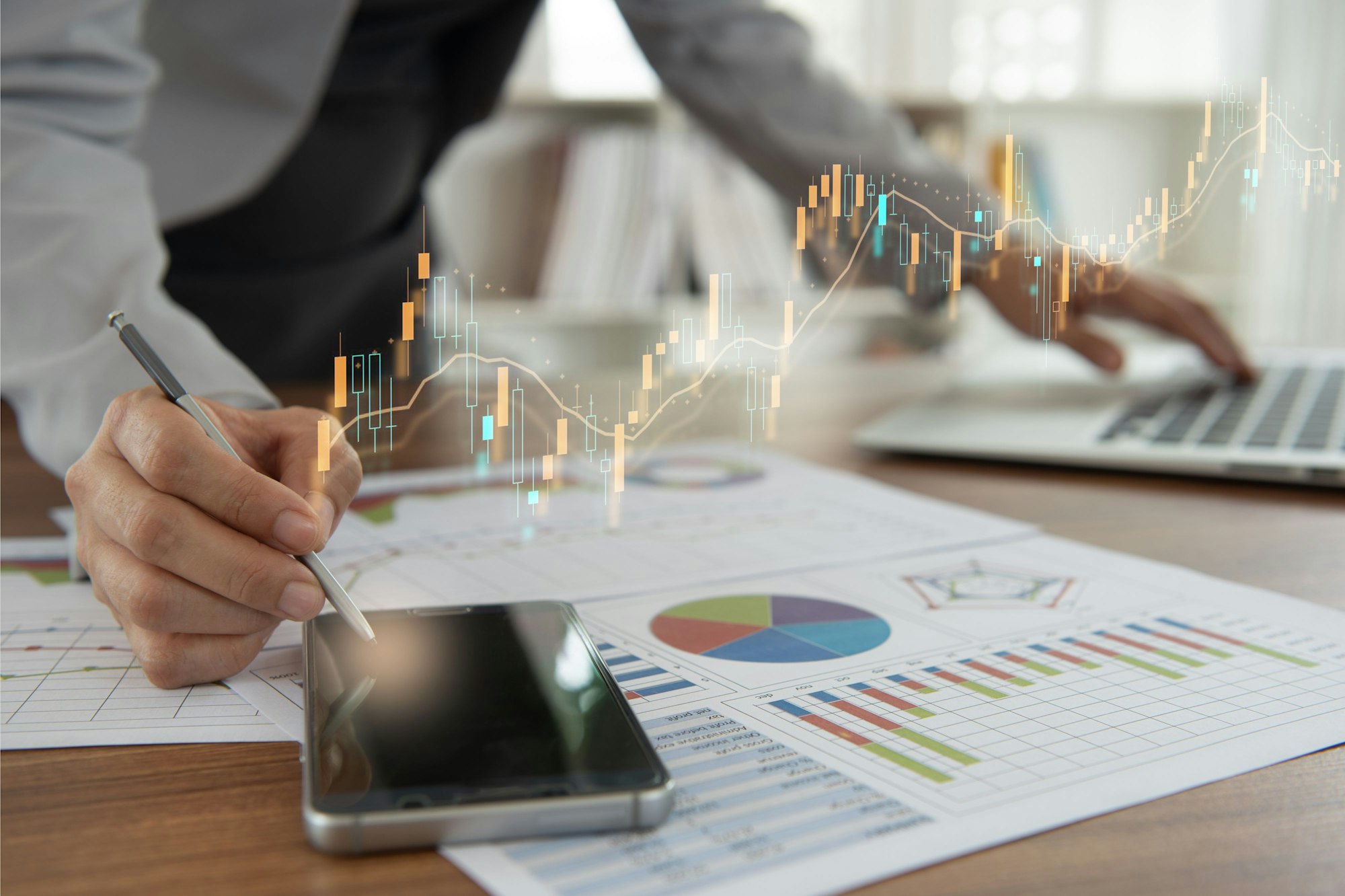 Das Bild zeigt einen Geschäftsmann am Schreibtisch. Auf dem Tisch liegen ausgedruckte Diagramme.