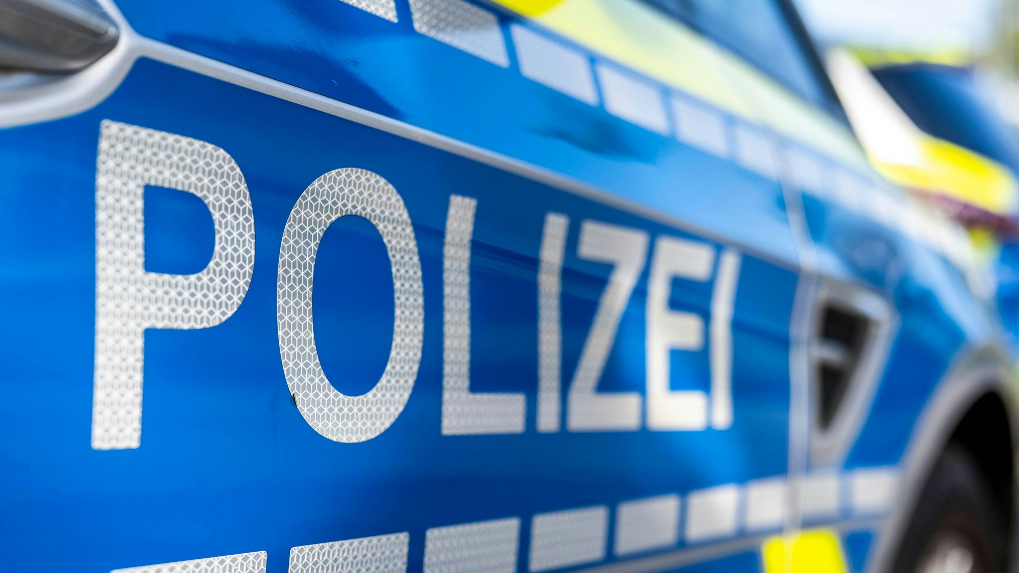 An der Tür von einem Streifenwagen steht der Schriftzug „Polizei“.
