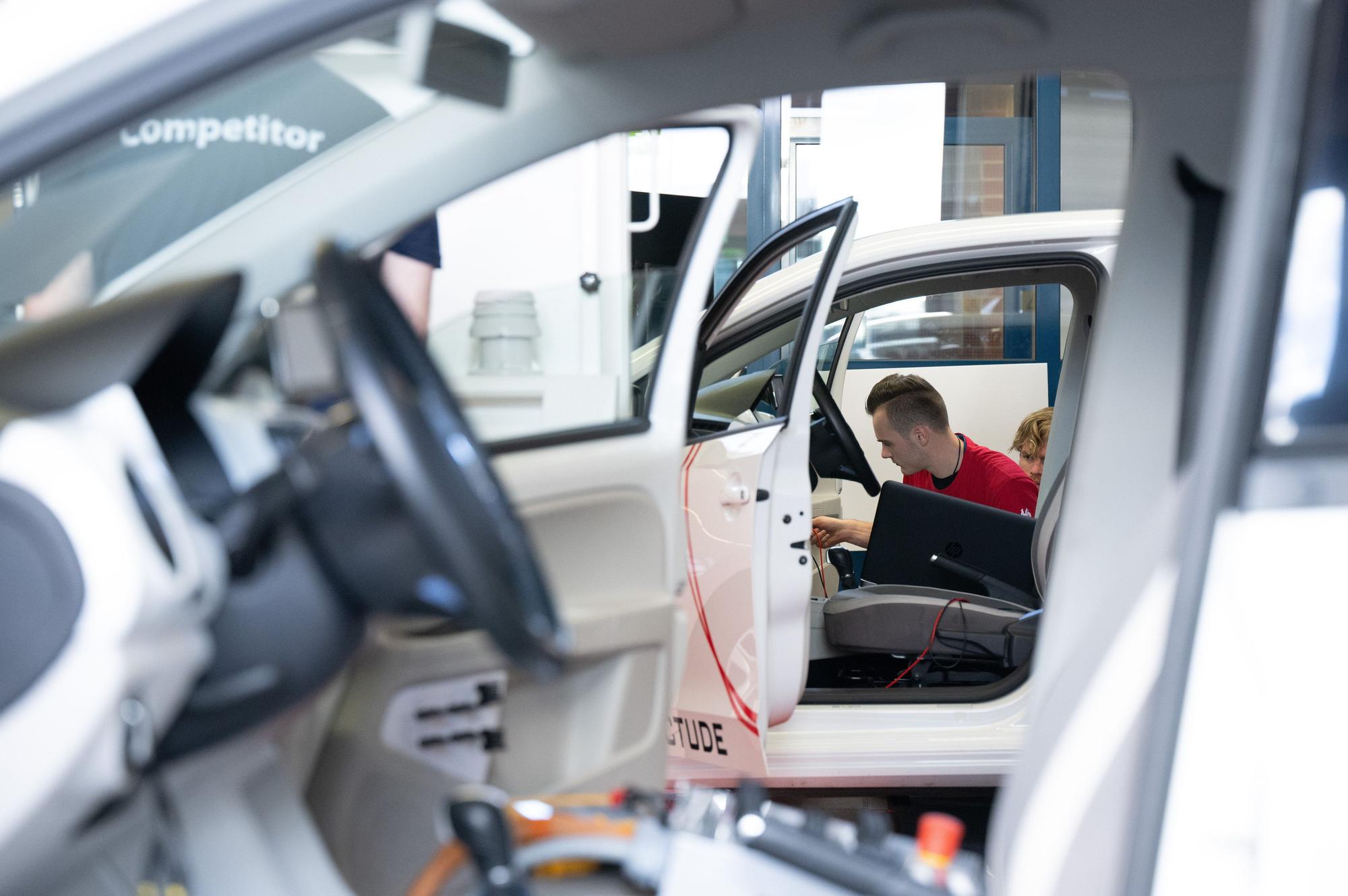 offene Autos, ein junger Mann im Hintergrund, der schraubt