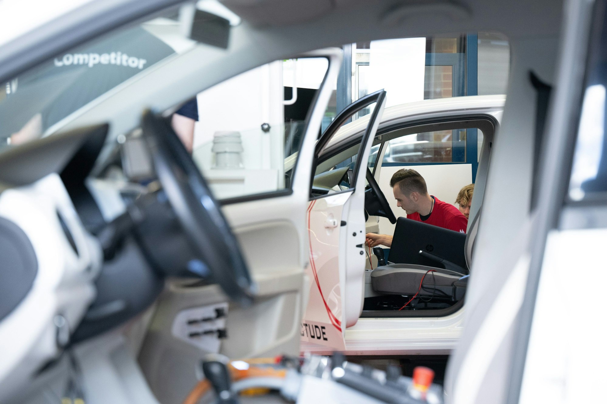 offene Autos, ein junger Mann im Hintergrund, der schraubt