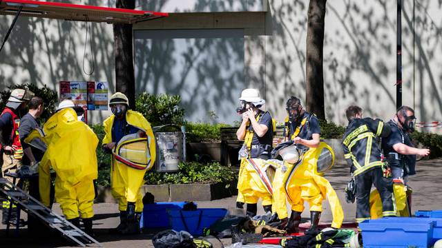 Das Bild zeigt zahlreiche Feuerwehrleute, die im Einsatz sind. Fünf von ihnen ziehen spezielle Schutzanzüge an.