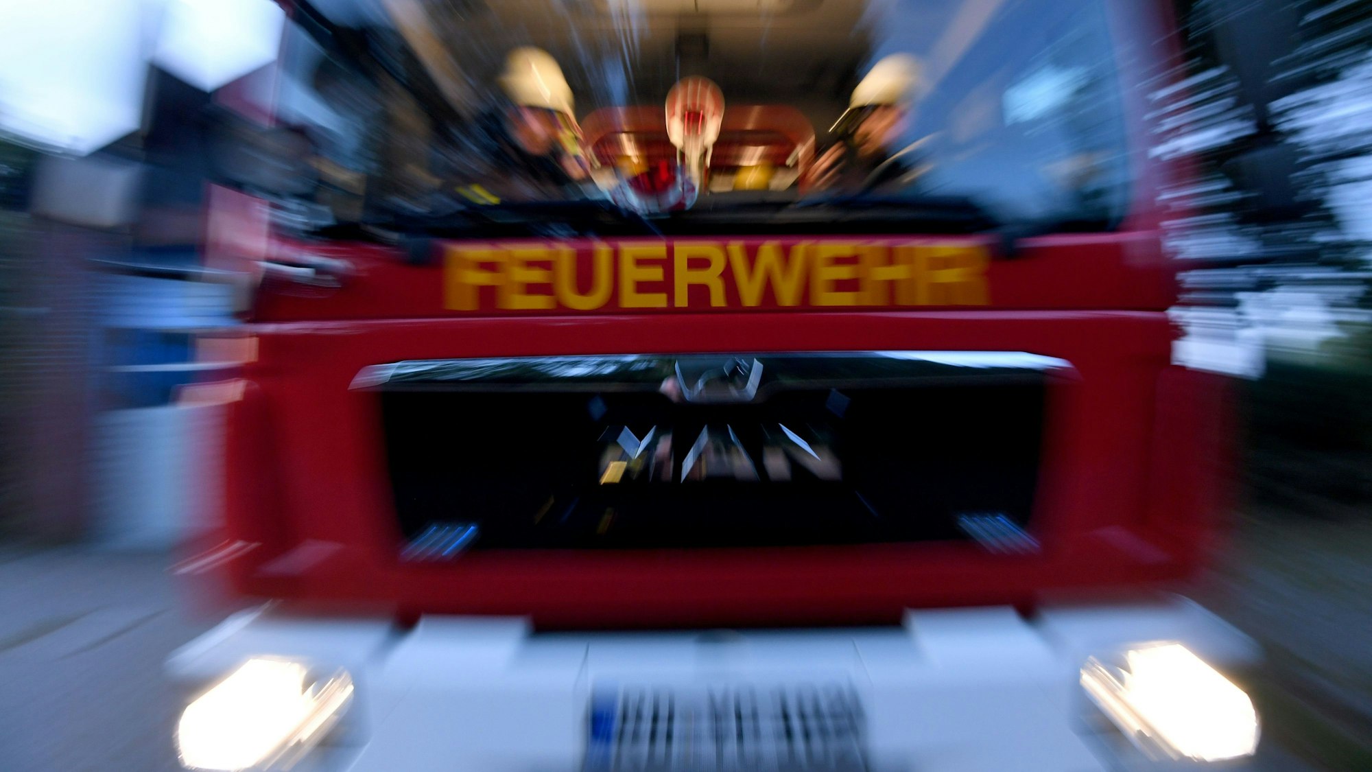 Einsatzkräfte der Feuerwehr sitzen in ihrem Fahrzeug.