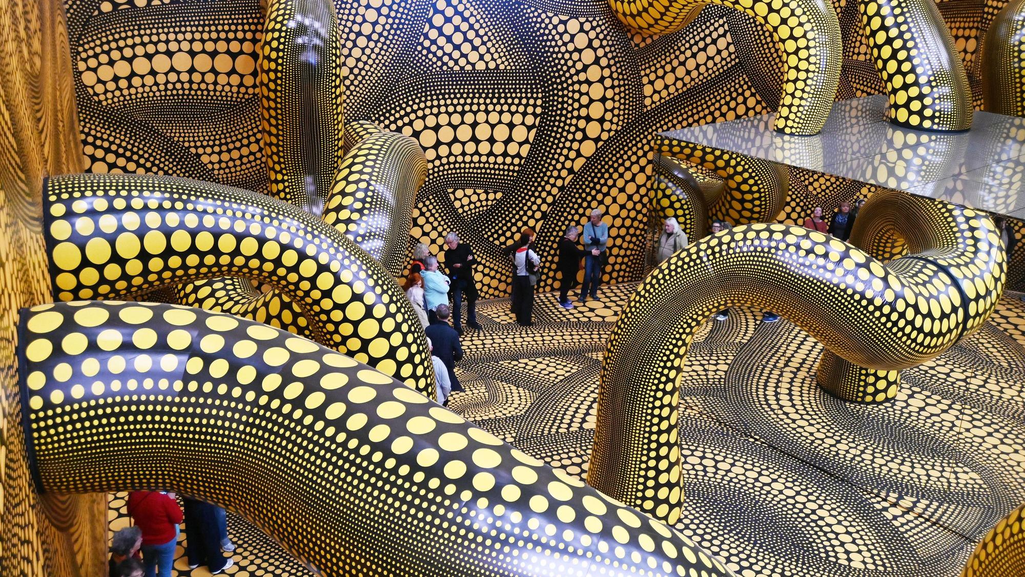 14.04.2026 Köln. Beate Wickenden und Ralph Peters sind die 100.000 Besucher in der Ausstellung Yayoi Kusama im Museum Ludwig. OB Torsten Burmester gratuliert. Foto: Alexander Schwaiger