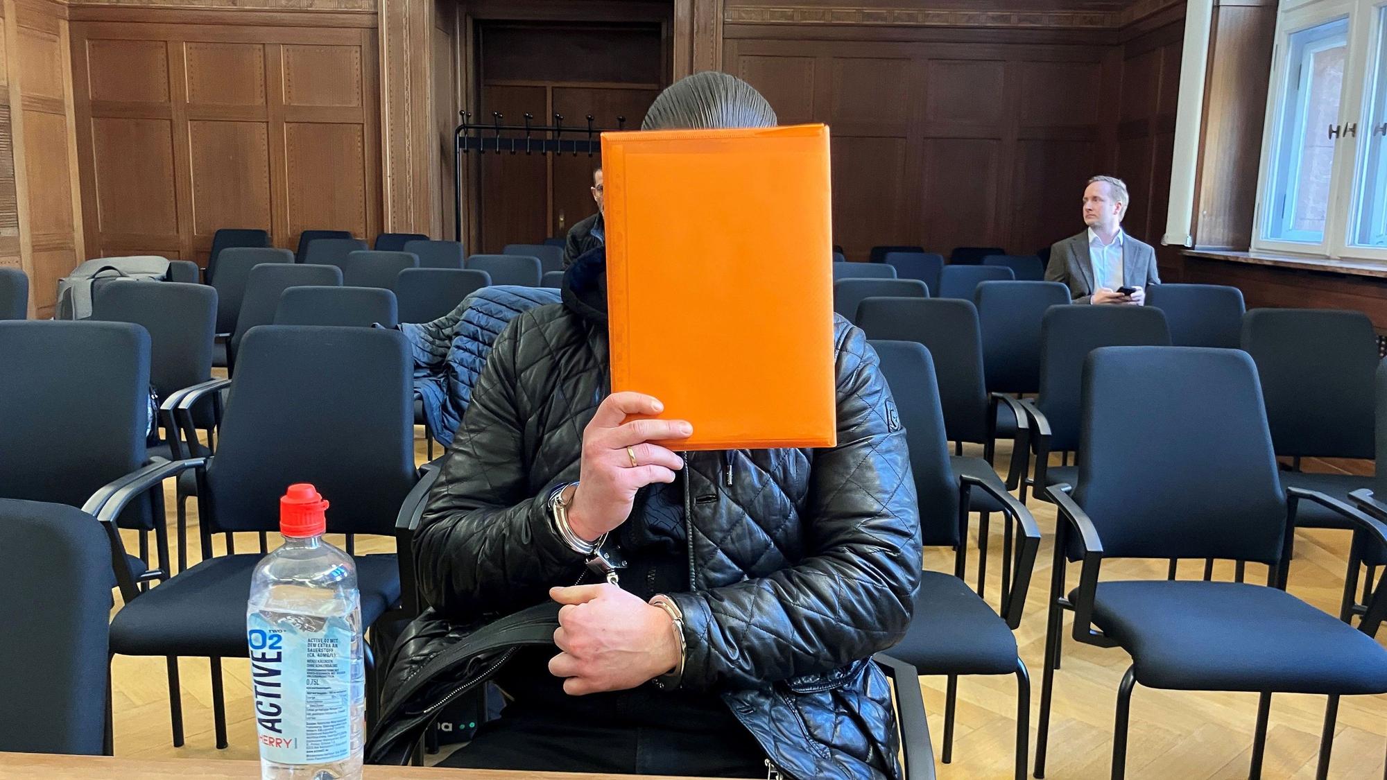 Der angeklagte Raser aus Duisburg sitzt im Verhandlungssaal des Verwaltungsgerichts Düsseldorf und hält sich eine Mappe vor das Gesicht. Nach einem tödlichen Autorennen verhandelte das Gericht über die Ausweisung des verurteilten Fahrers in den Kosovo.