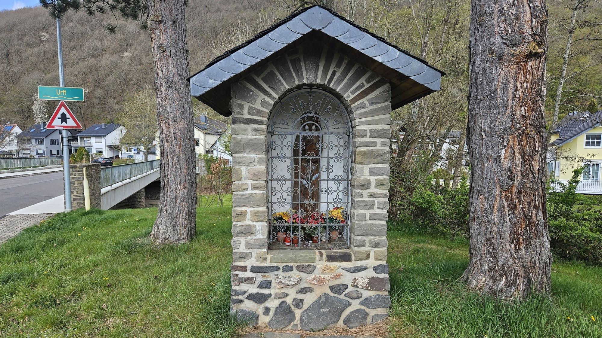 Blick auf die Mariengrotte in Gemünd-Malsbenden. Ein Bau aus Natursteinen mit einem Dach mit Schieferplättchen.