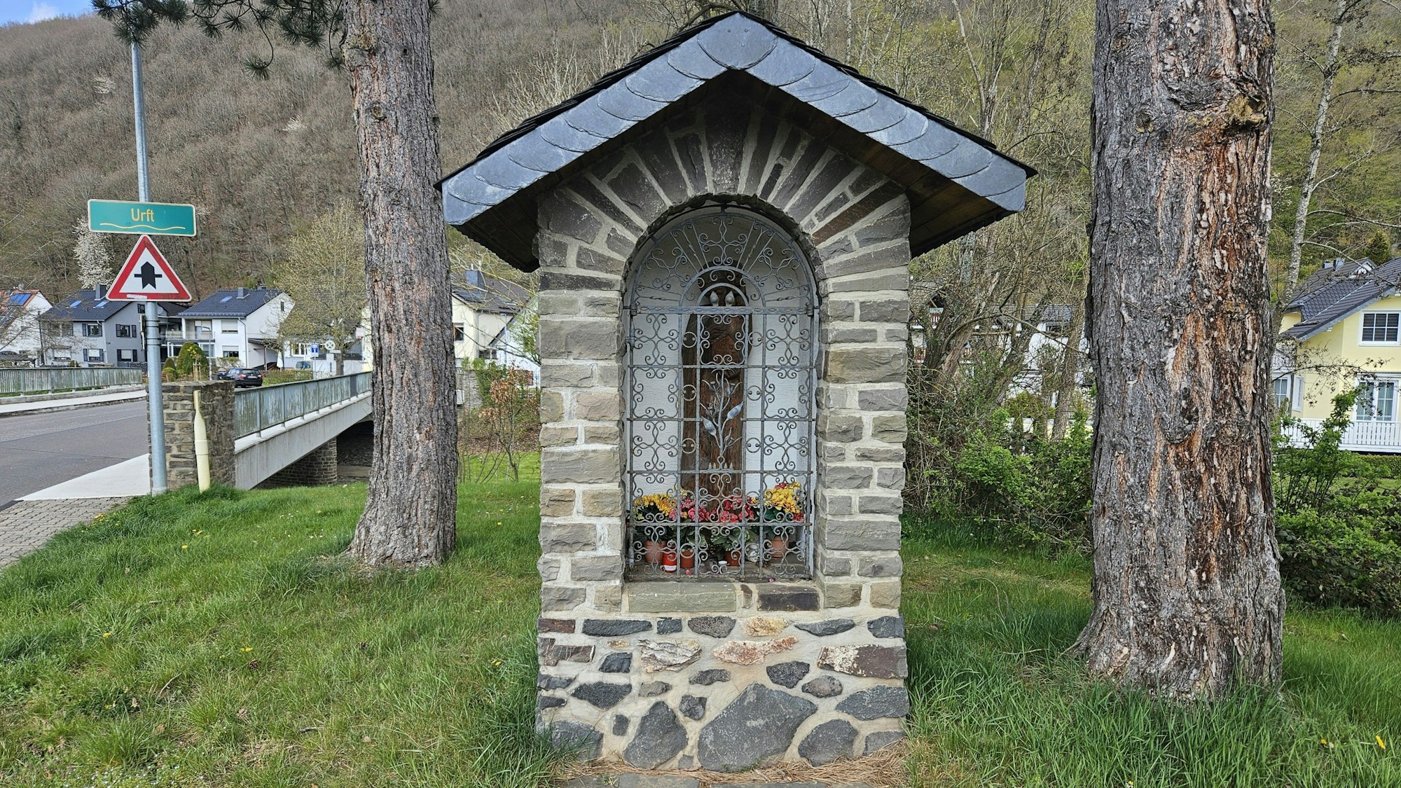 Blick auf die Mariengrotte in Gemünd-Malsbenden. Ein Bau aus Natursteinen mit einem Dach mit Schieferplättchen.