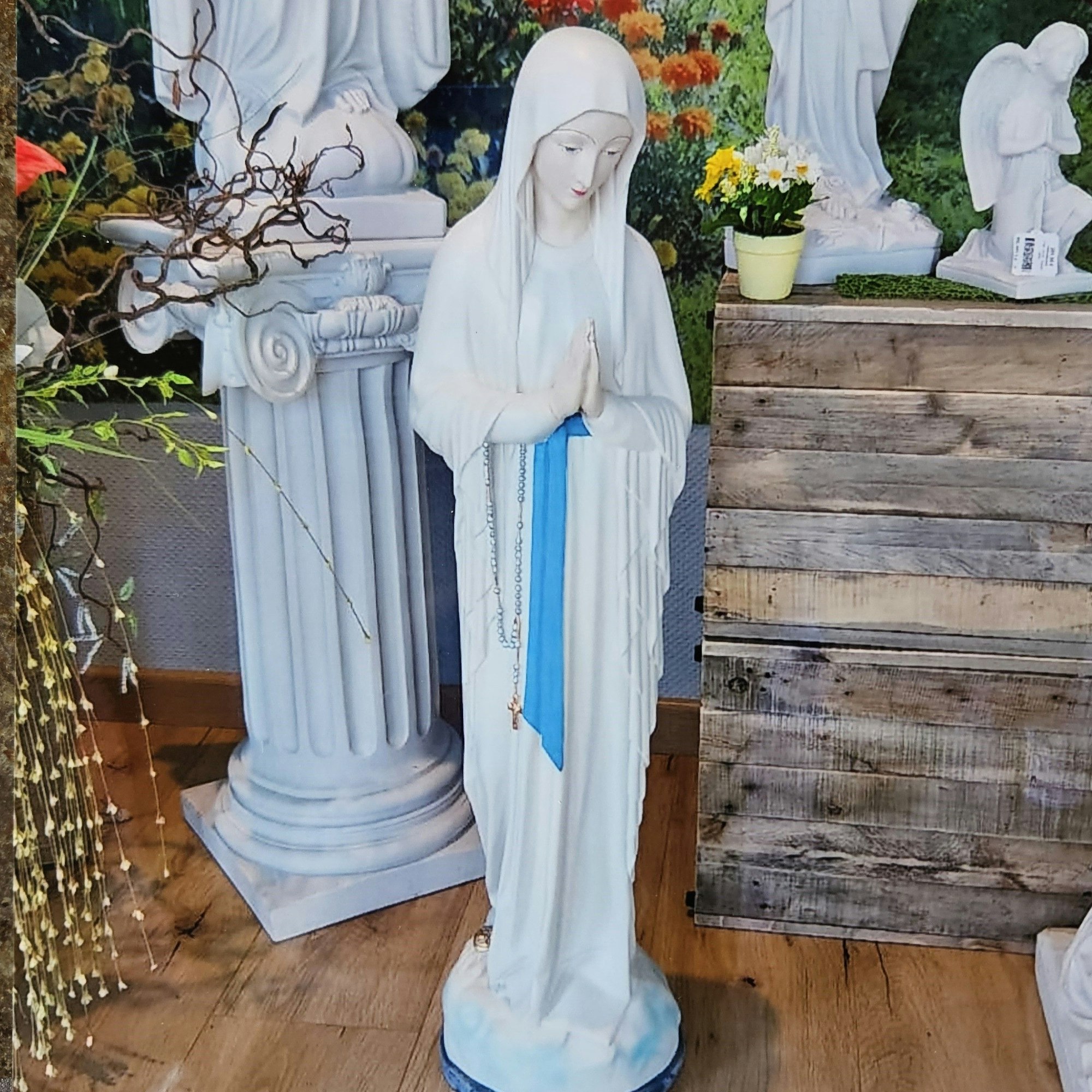 Das Foto zeigt eine weiße Marienfigur mit betenden Händen.