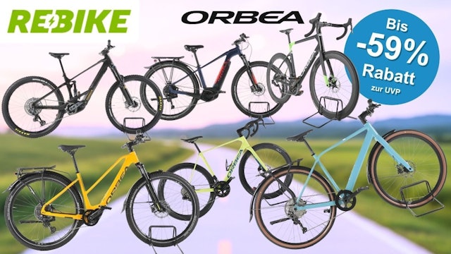 Fünf refurbished Orbea-Fahrräder und E-Bikes unterschiedlicher Kategorien – darunter ein E-Mountainbike, ein Trekking-E-Bike, ein Gravelbike und ein City-Bike – vor einem unscharfen Straßen- und Landschaftshintergrund. Im Bild die Logos von Rebike und Orbea.