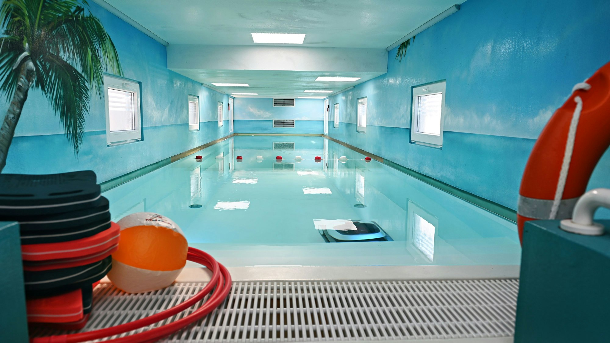 Blick auf das Schwimmbecken, die blauen Wände und die weiße Decke.