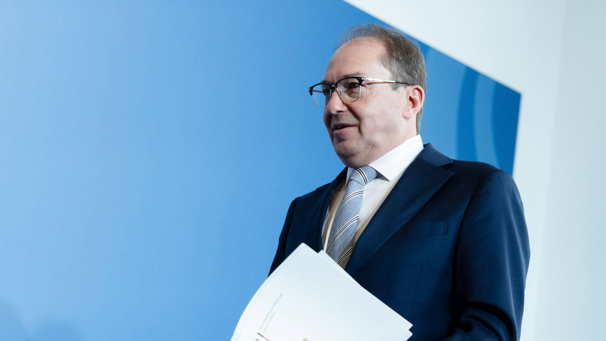 Alexander Dobrindt hält Papiere im Anzug