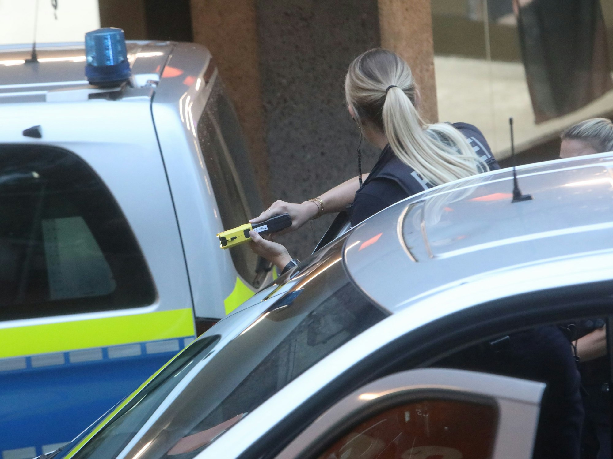 Eine Polizistin zwischen Polizeiautos