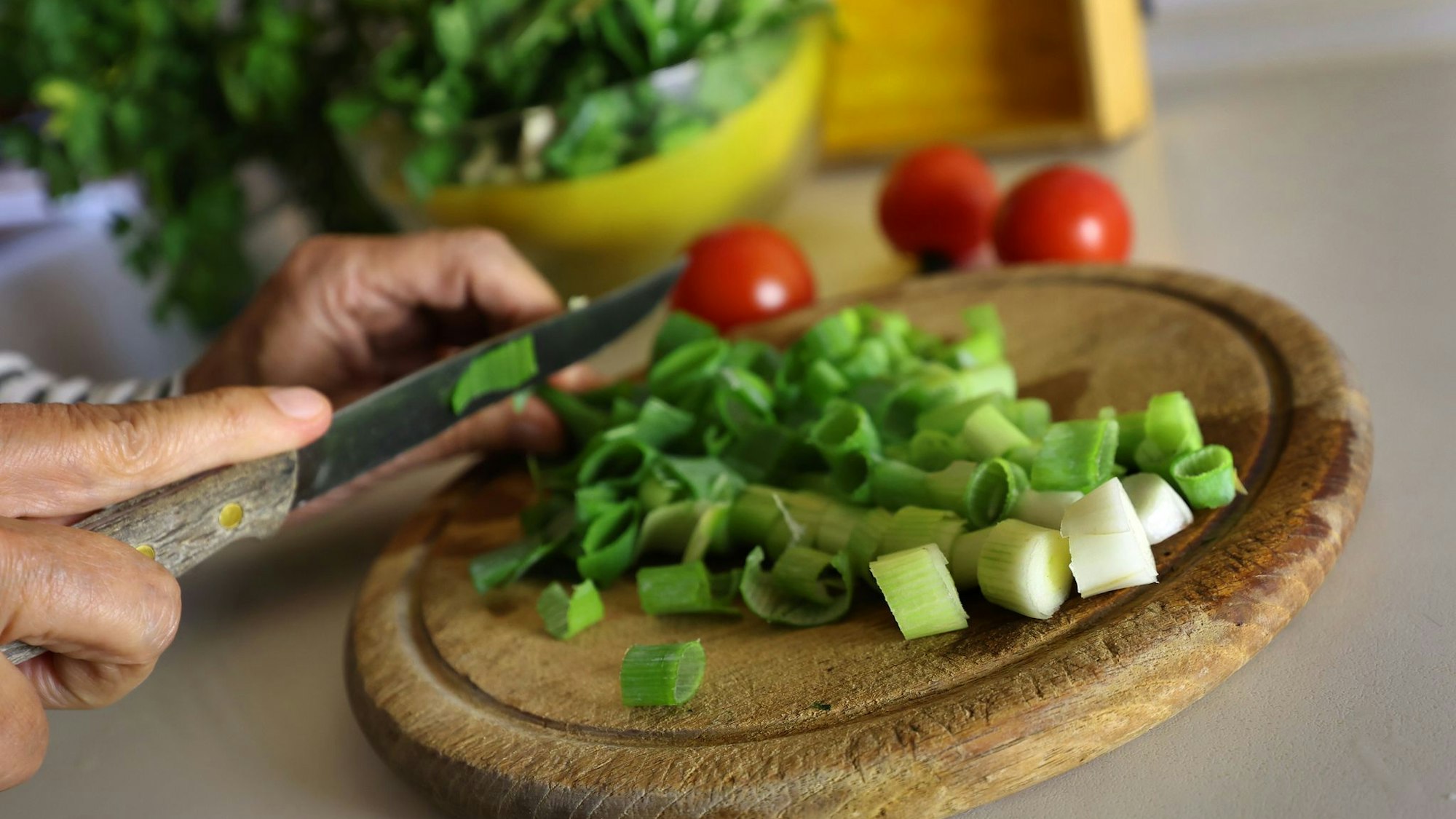 Eine Frau schneidet beim Kochen Lauchzwiebeln
