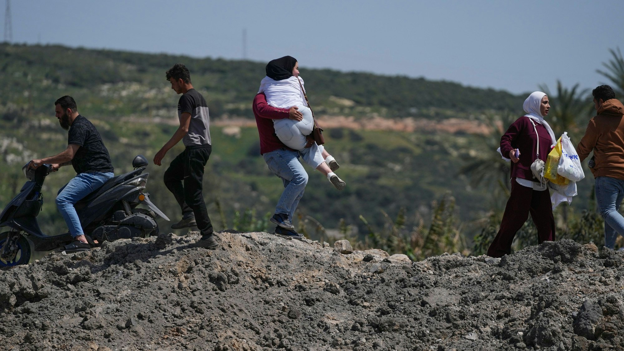 Ein Mann trägt eine Frau, während sie zu Fuß eine zerstörte Brücke überqueren, die bei einem israelischen Luftangriff nahe der Küstenstadt Tyrus im Südlibanon getroffen wurde.