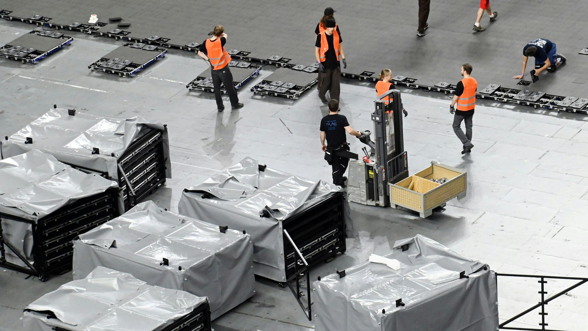 Arbeiter in der Lanxess-Arena bauen einen LED-Boden auf