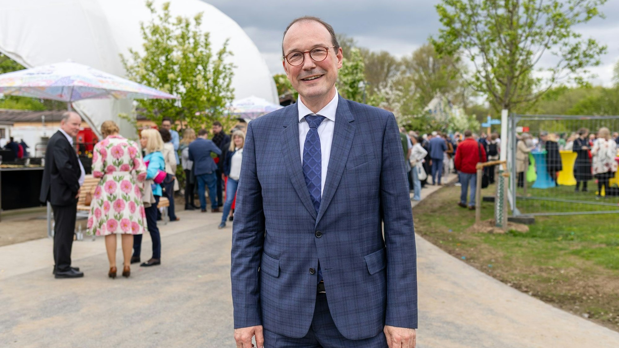 Ein Mann im Anzug steht vor einer Menschentraube.