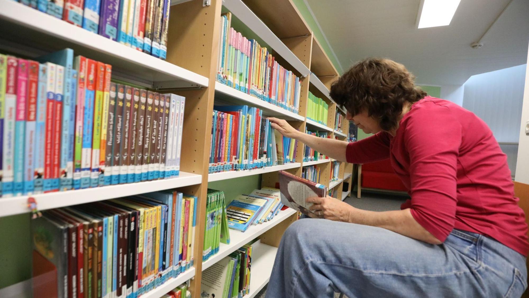 Eine Frau vor einem Bücherregal.