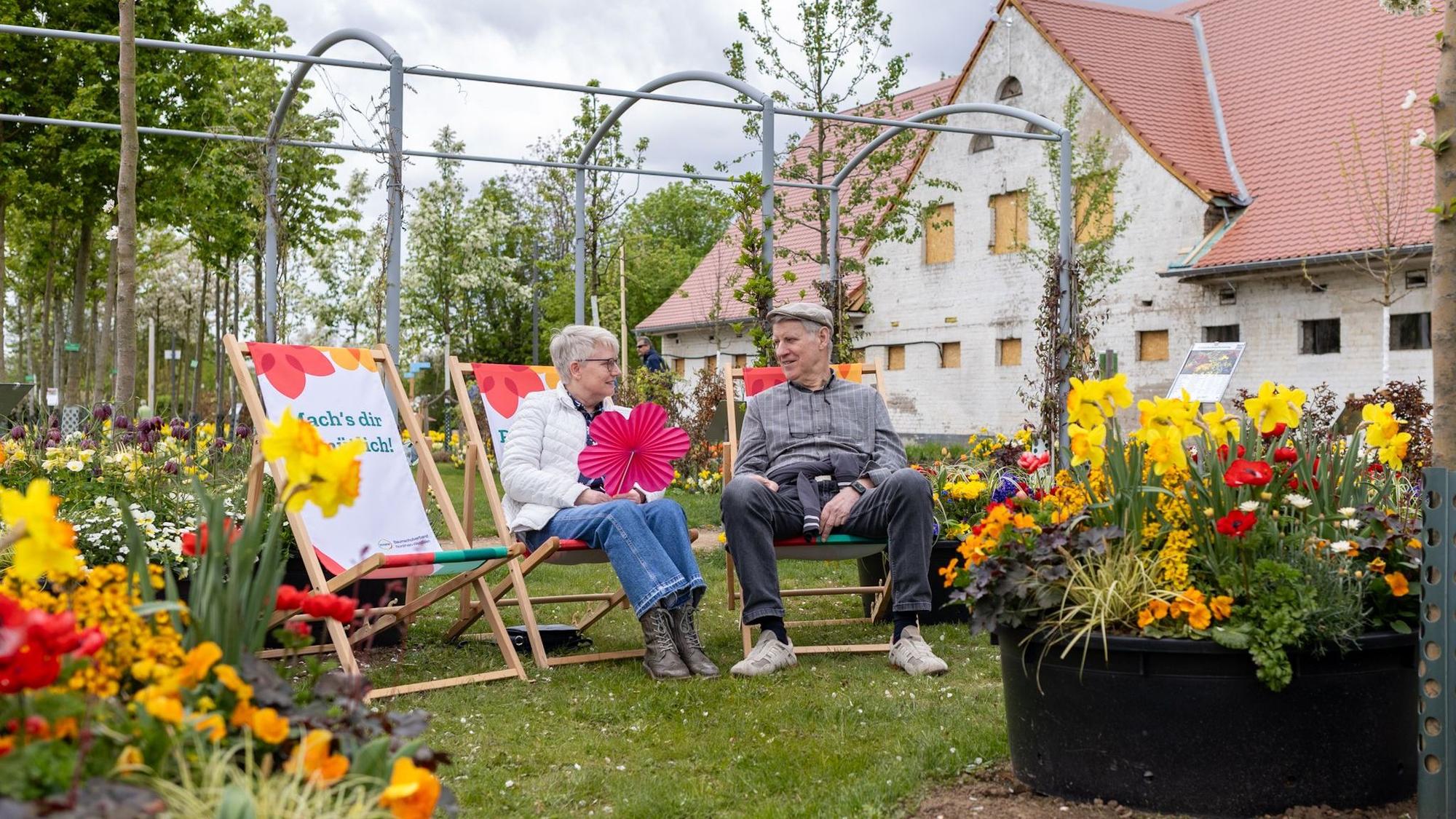 Zwei Senioren sitzen jeweils auf einem Liegestuhl und unterhalten sich.