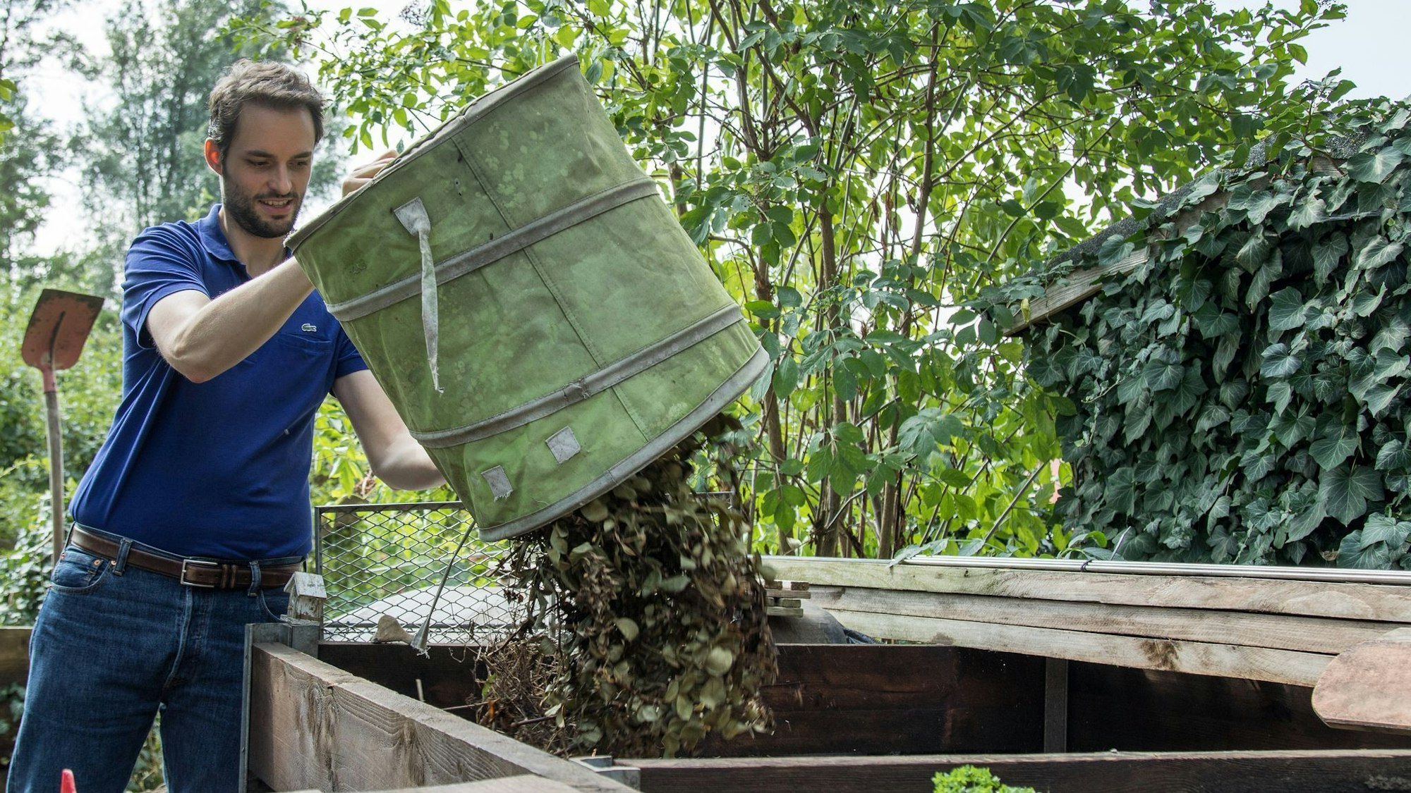 Mann entsorgt Pflanzenreste auf dem Kompost