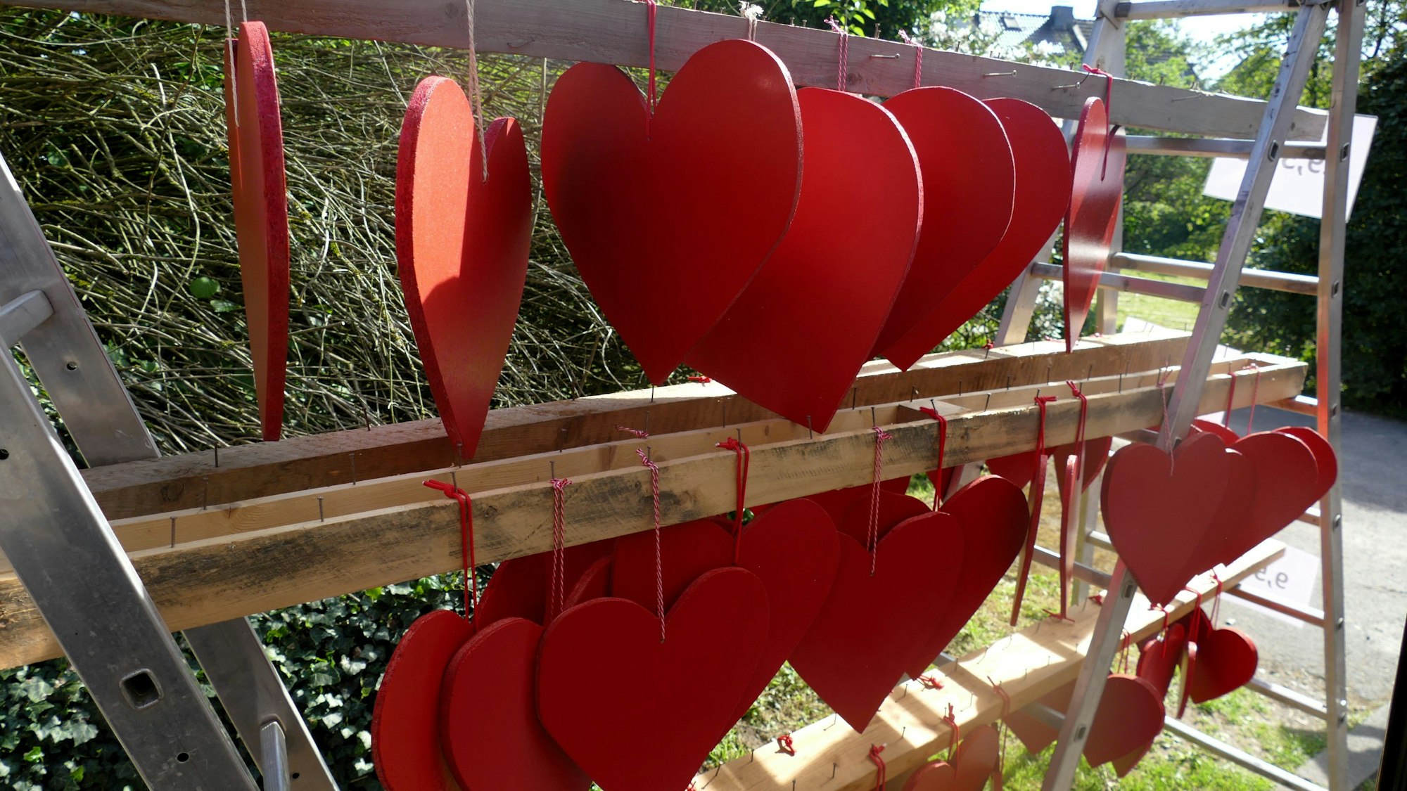 Rote Herzen aus Sperrholz hängen an einem Verkaufsgestell.