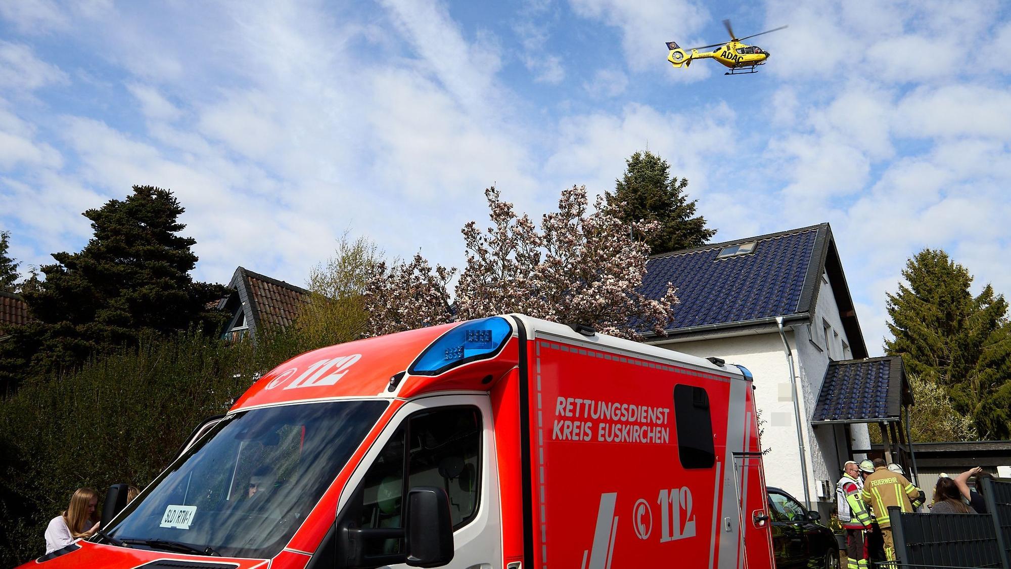 Der ADAC-Rettungshubschrauber fliegt über das Haus, davor ein Rettungswagen und Einsatzkräfte.