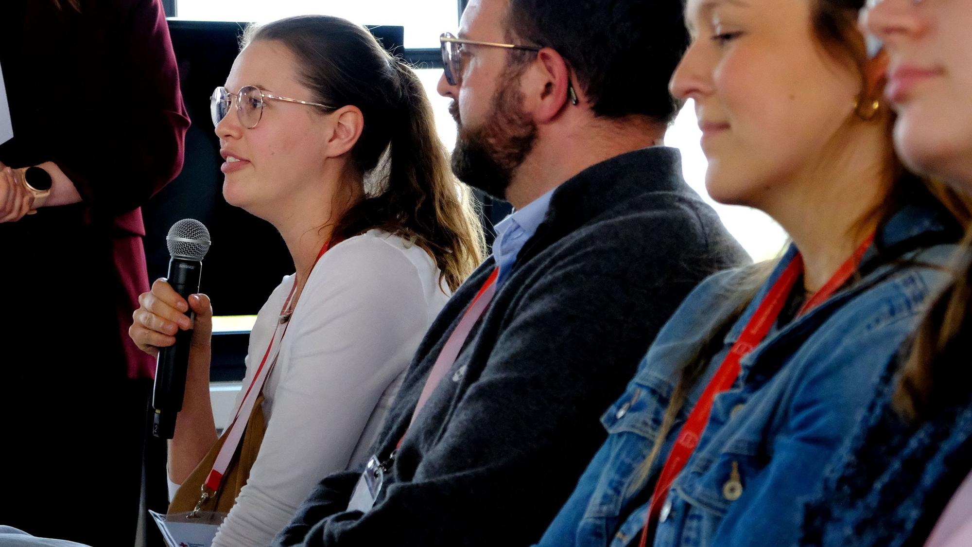 Auftaktveranstaltung des Euskirchener Ärztedialogs: Laura Schwanke stellt eine Frage aus dem Plenum, hat dabei ein Mikrofon in der Hand.