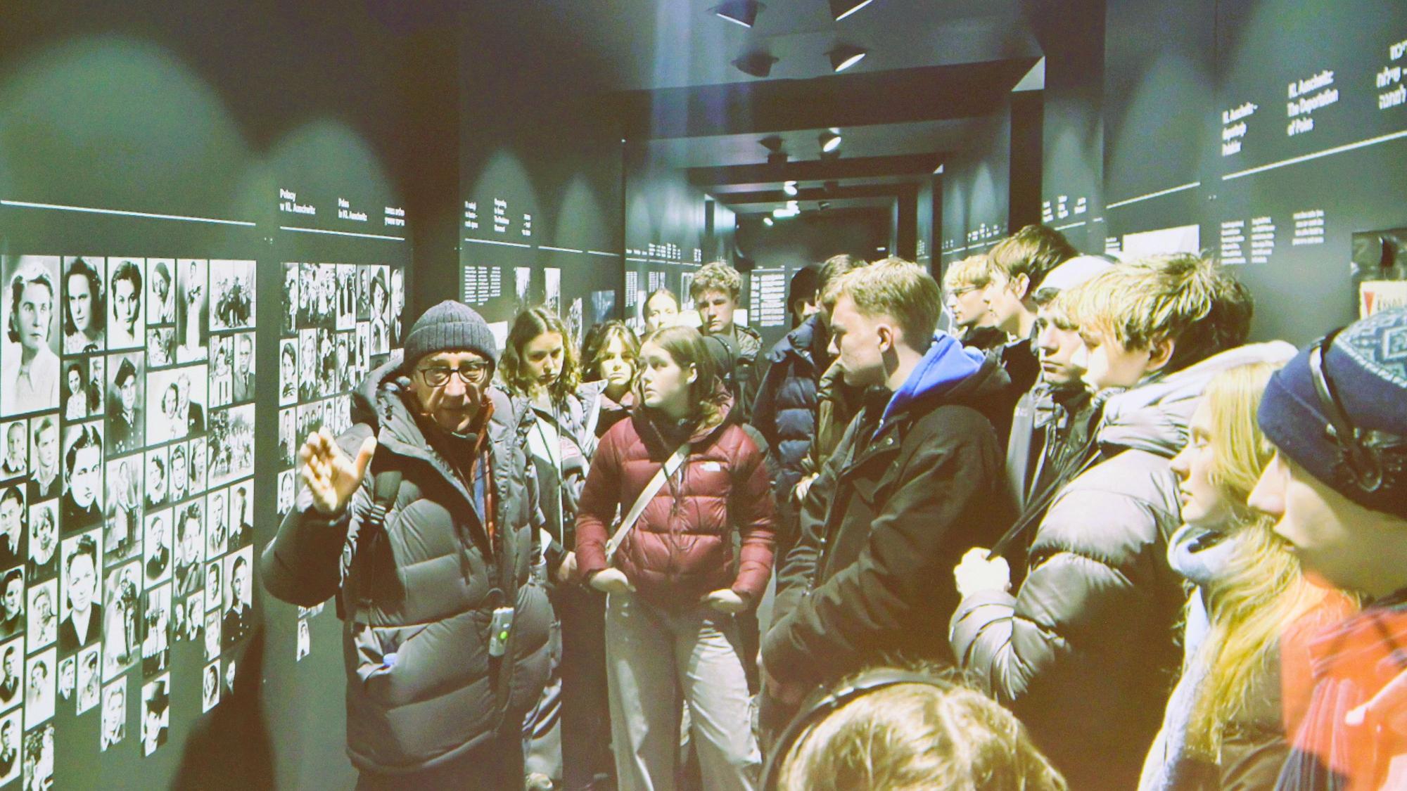 Schüler stehen vor einer Wand mit Schwarz-Weiß-Fotos.