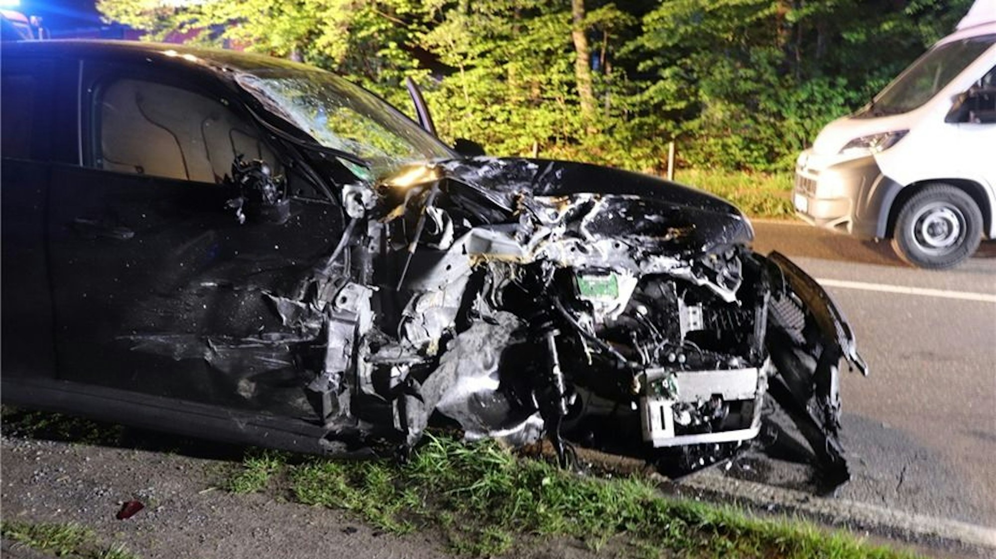 Ein stark beschädigter Mercedes AMG steht nach einem Unfall auf der Straße.
