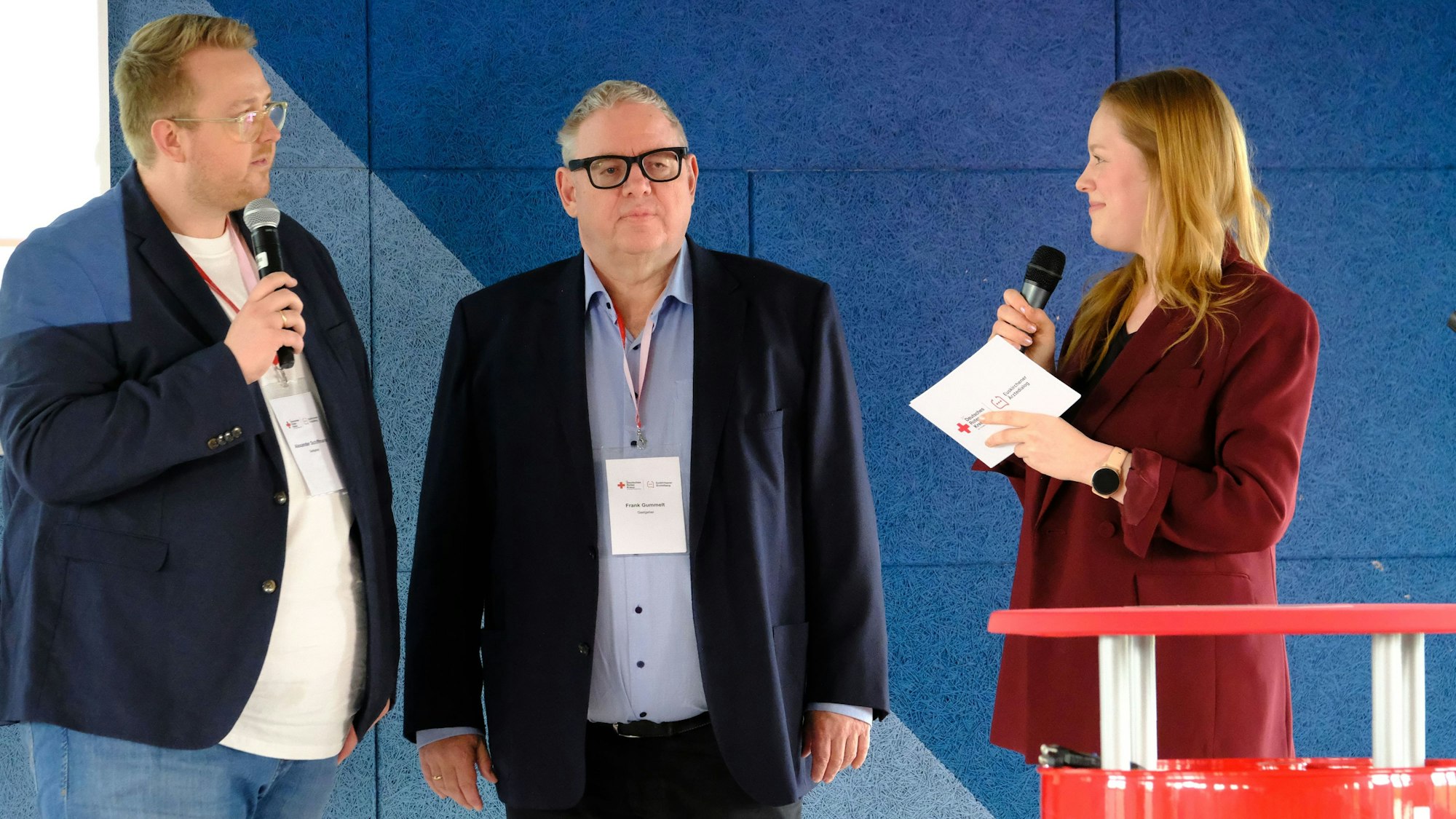 Alexander Schiffmann (DRK), Frank Gummelt, Kreisverbandsarzt und Kreisvorsitzender der KVNO, und Moderatorin Magdalena Gorecki (v.l.) stehen auf der Bühne.
