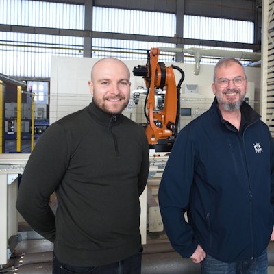 Die drei Männer stehen in einer Halle des Unternehmens.