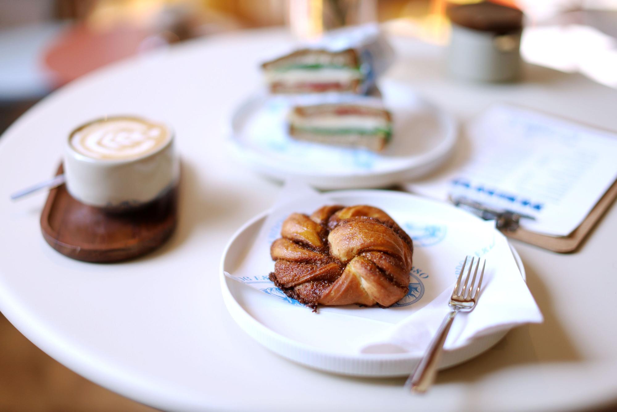 Gedeckter Tisch mit Kaffee, einem Gebächstück und Sandwiches ist zu sehen.